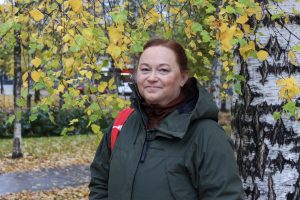 Minna Rantapää står vid en björk och ler mot kameran.